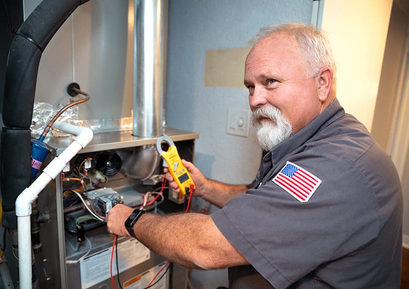 A technician with meter inspecting a residential gas furnace