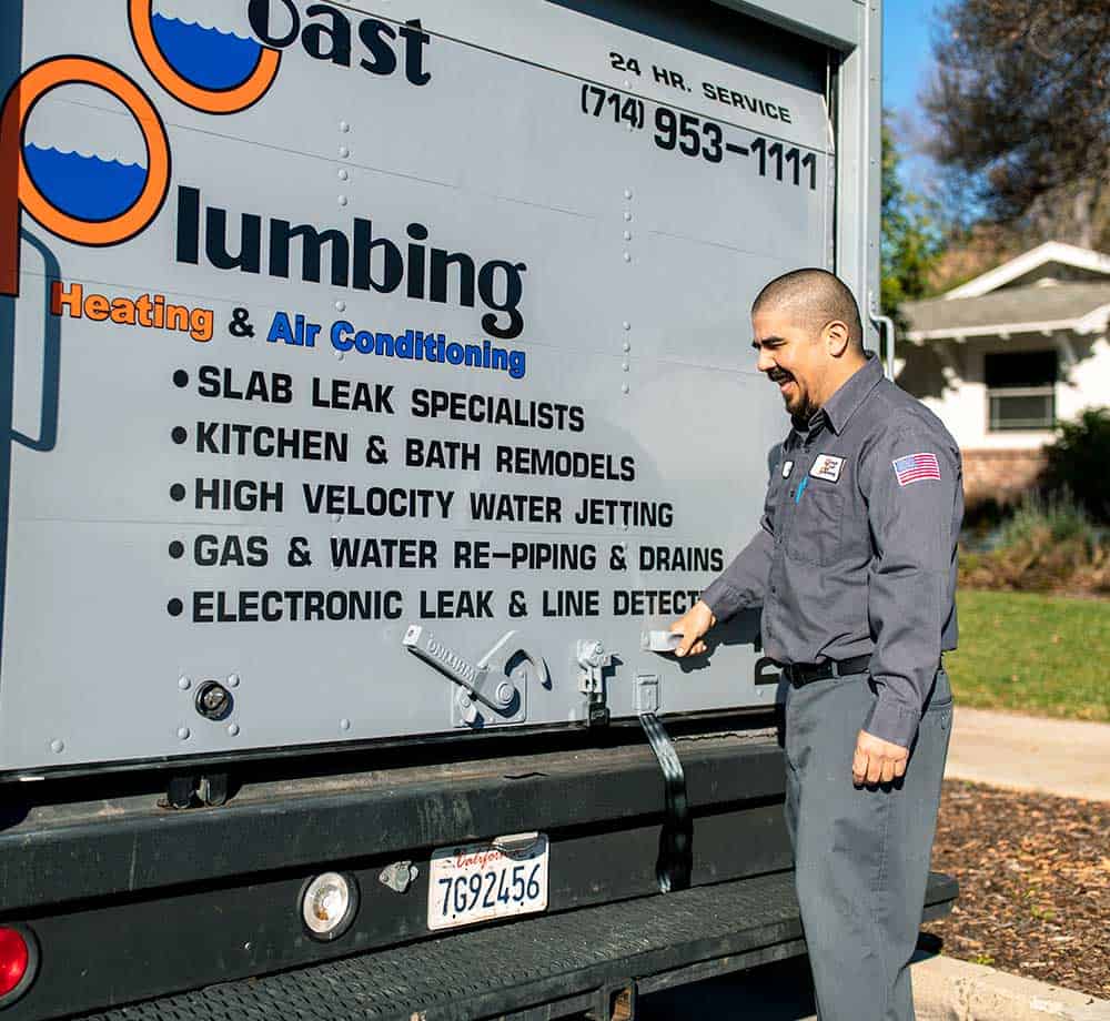 A plumbing tech with service truck in front of residential home