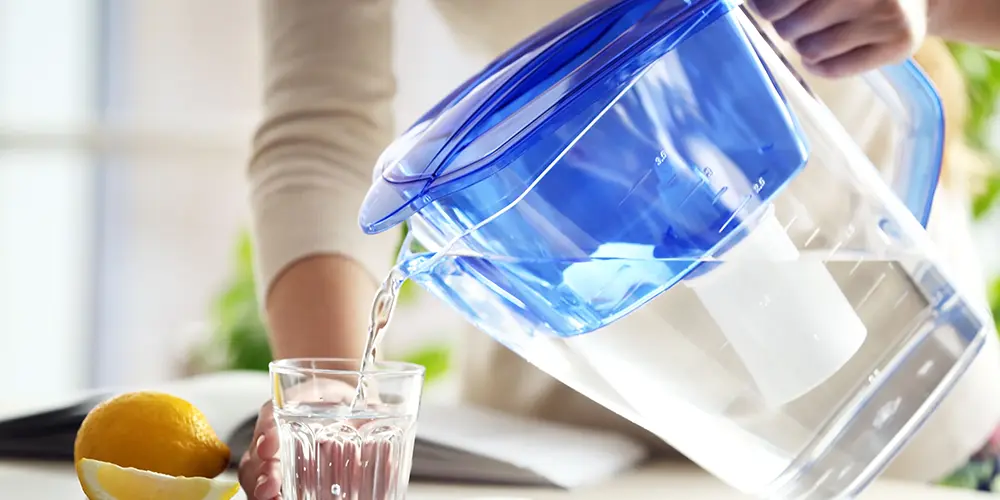 A woman pours a glass of filtered water
